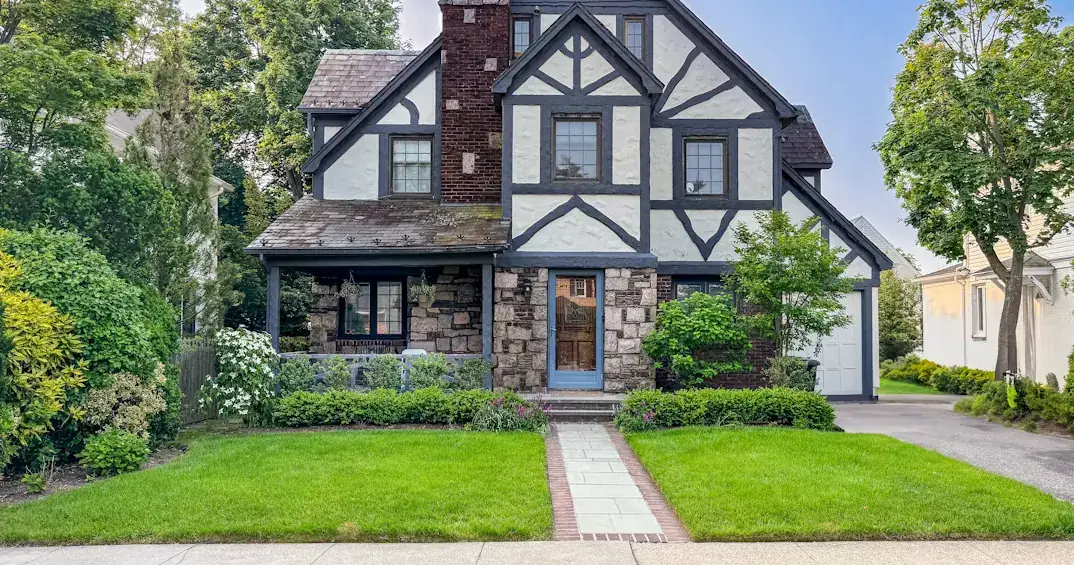 Freshly mowed front lawn split by a brick-edged stone walkway, with trimmed hedges along the house