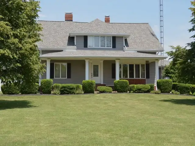 Wide, evenly mowed lawn in front of a house with rounded shrubs